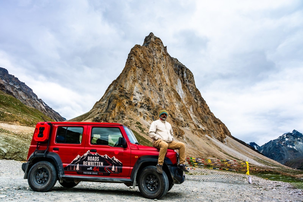 Alok sitting on the red Suzuki Jimny in front of Gonbo Rangjon peak in Zanskar