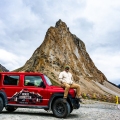 Alok sitting on the red Suzuki Jimny in front of Gonbo Rangjon peak in Zanskar