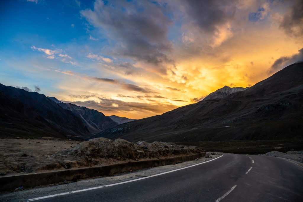 Winding mountain road in Ladakh under a golden sunset sky