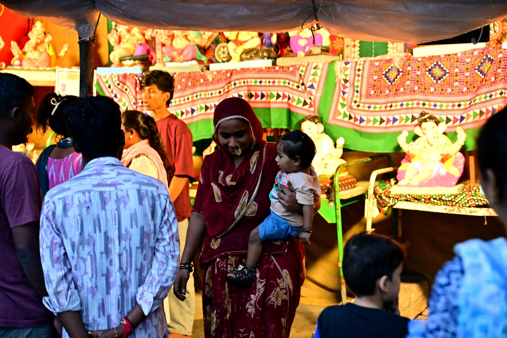 A woman with her child walking past rows of Ganesh idols in Gulbai Tekra ahead of Ganesh Chaturthi