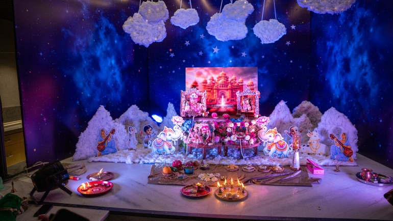 Janmashtami decoration at home with cotton-cloud mountains, cutouts of gopis and elephants, and a Laddu Gopal jhula against a Vrindavan palace backdrop